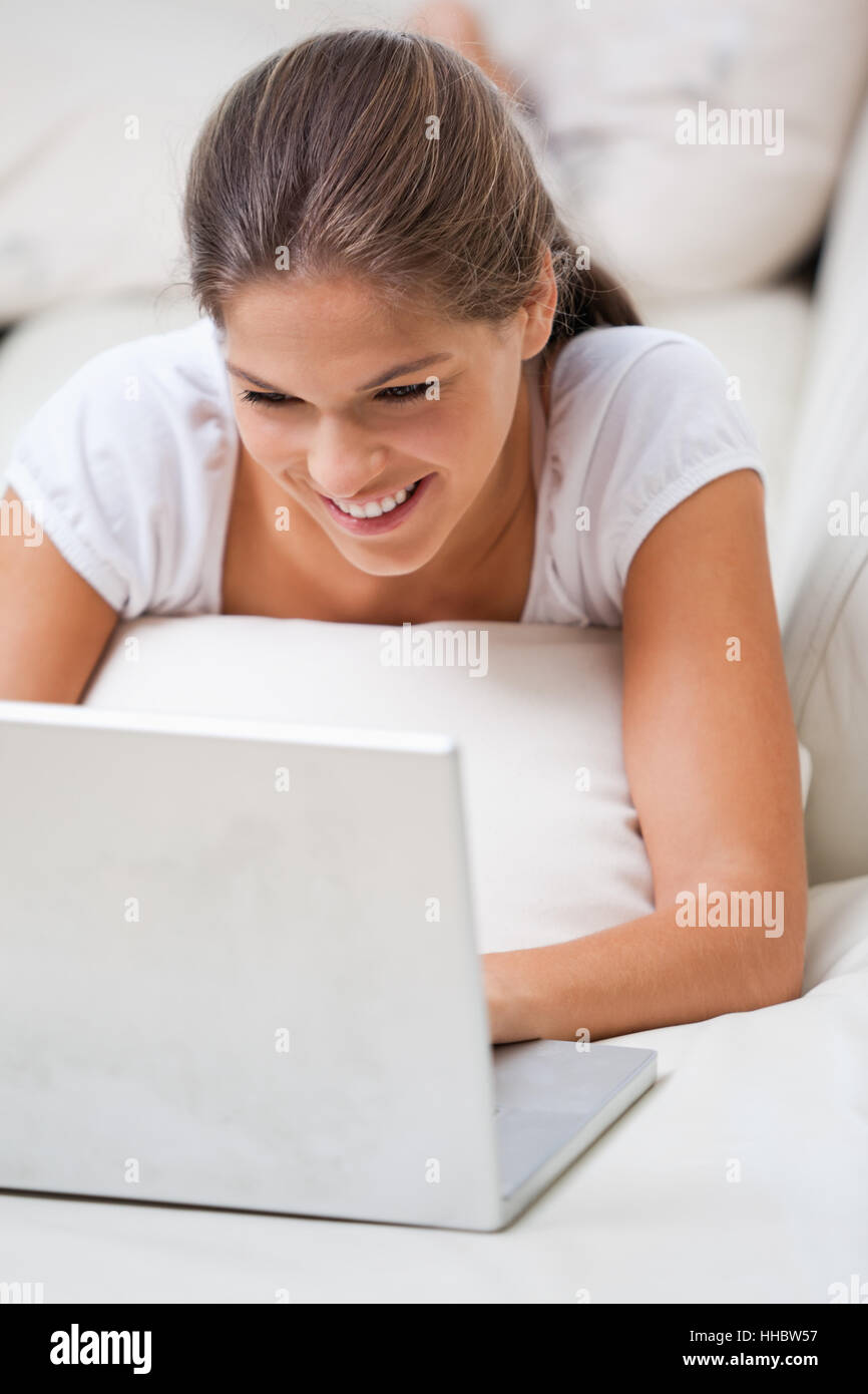 Woman lying on a sofa while using a laptop indoors Stock Photo - Alamy