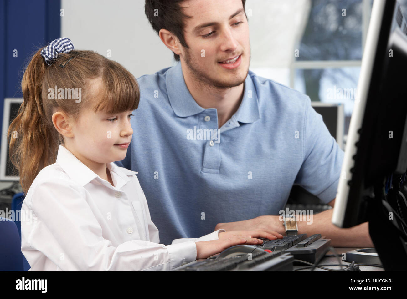 Teacher helping girl using computer in class Stock Photo - Alamy