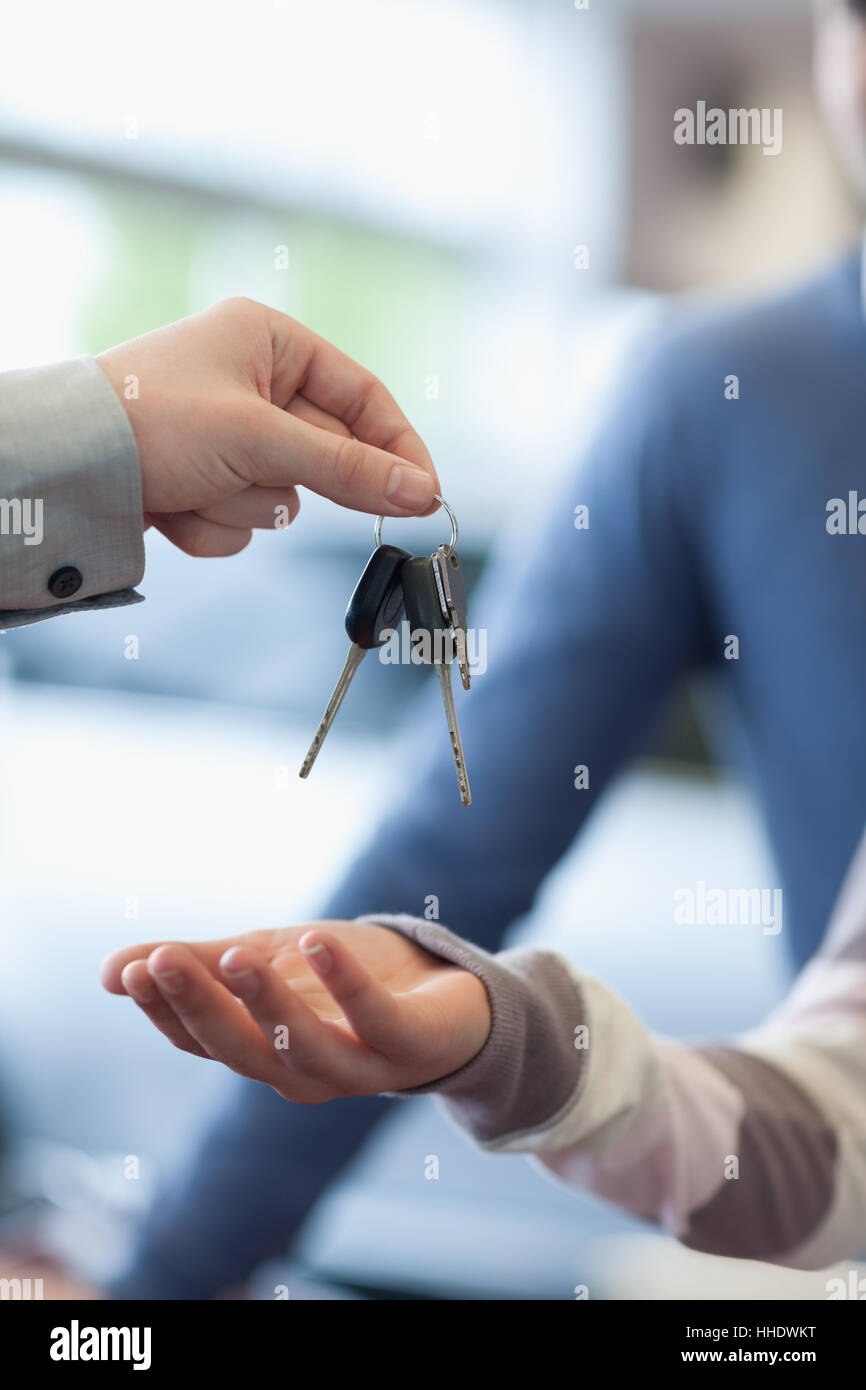 Salesman holding keys over the hand of a customer in a carshop Stock Photo