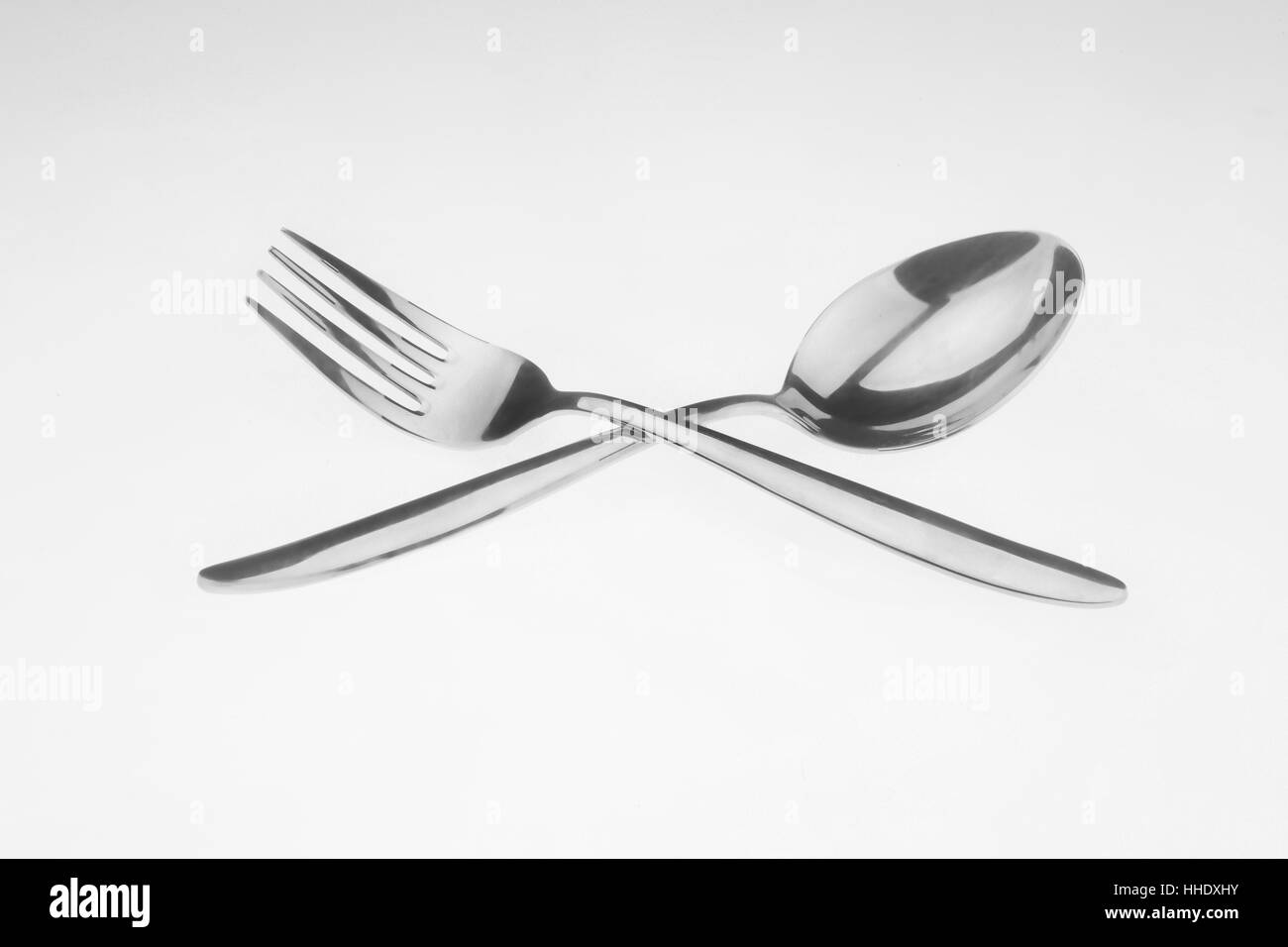 Fork and spoon crossed on white surface Stock Photo