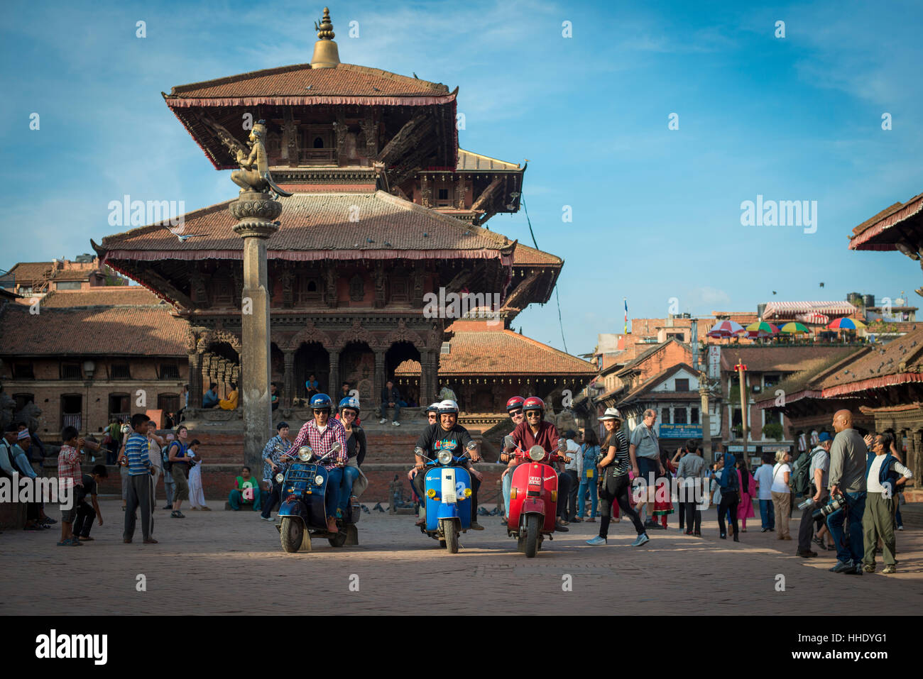 A group of tourists sit with their scooters in the historical temple