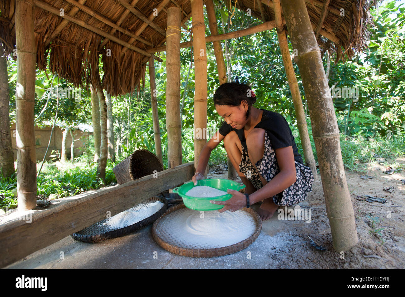 A woman mills grain into flour using a tradiional mill, Chittagong Hill Tracts, Bangladesh Stock Photo