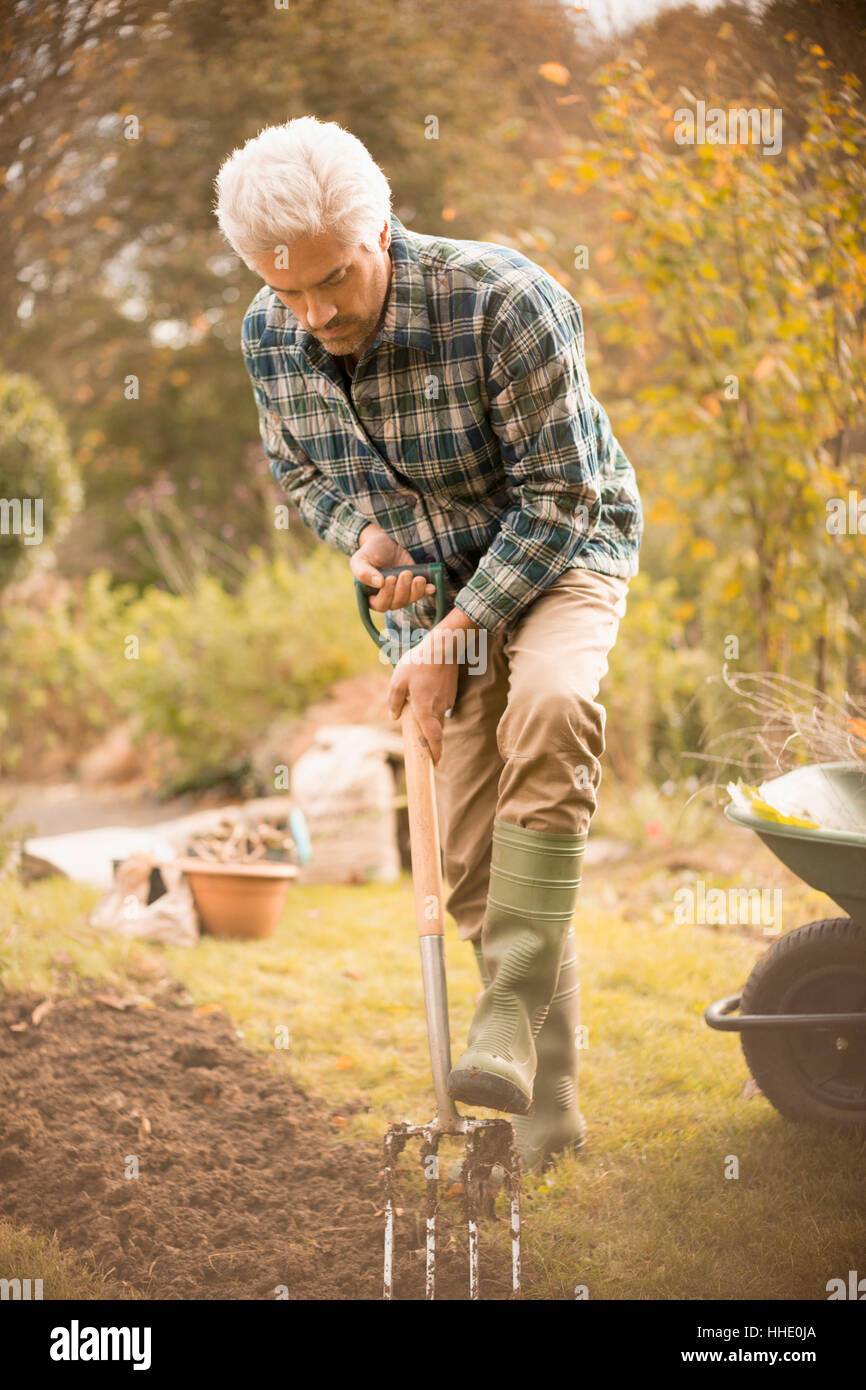Man gardening digging dirt in autumn garden Stock Photo