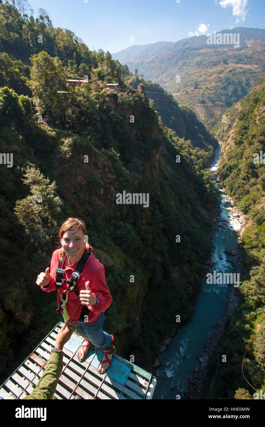 Standing on then edge, a girl prepares herself to take a bungy jump backwards, Nepal Stock Photo