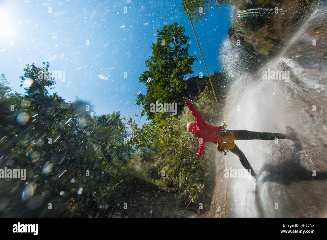 A man pauses to hold his arms in the falling water while canyoning in Nepal Stock Photo