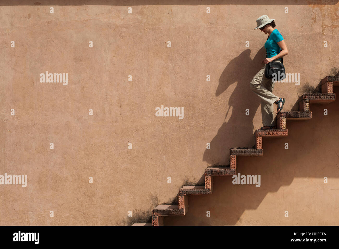 A tourist climbs downs some exposed steps within the Fatehpur Sikri temple complex, Uttar Pradesh, India Stock Photo