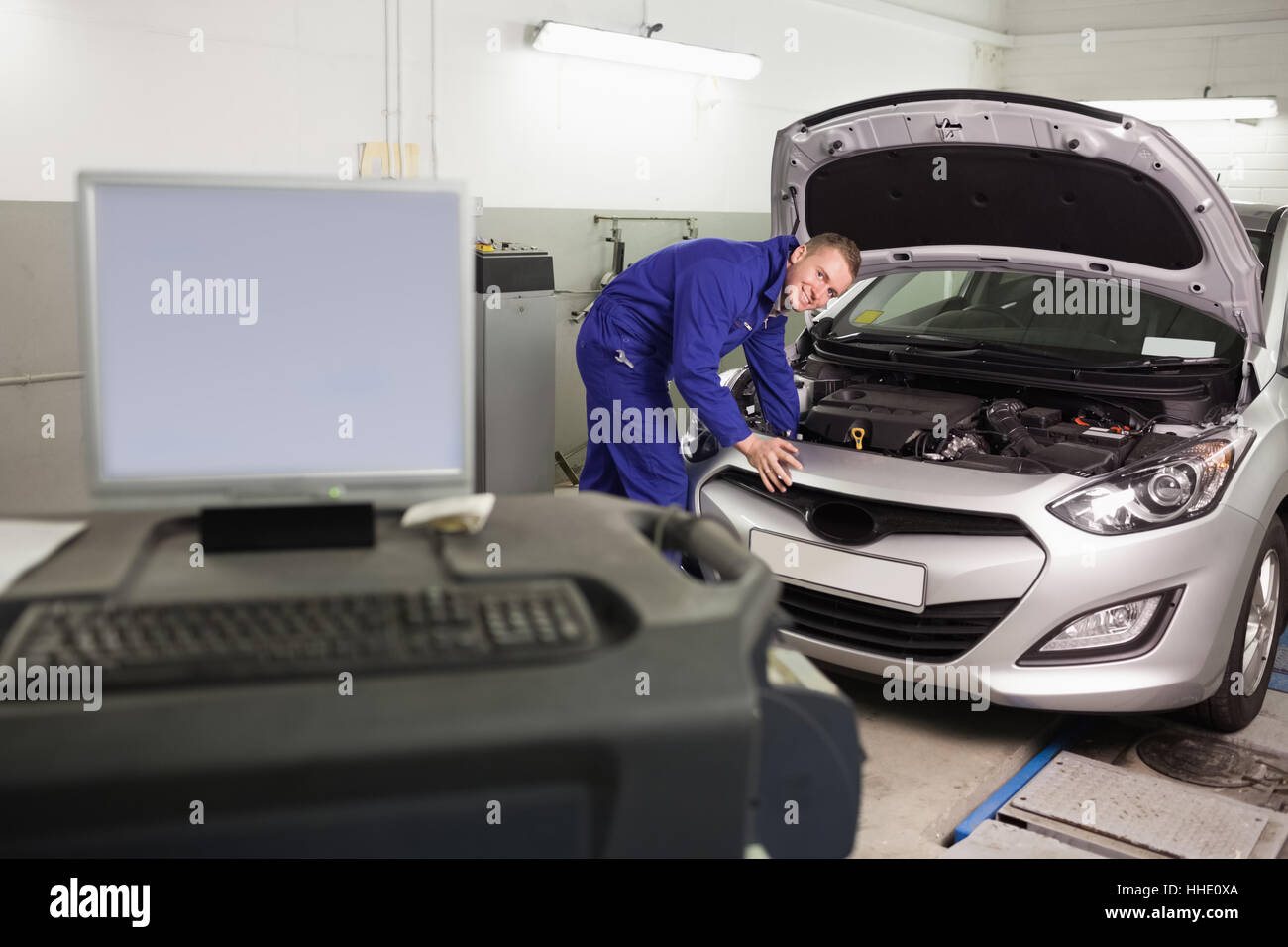 Smiling mechanic examining a car engine in a garage Stock Photo - Alamy