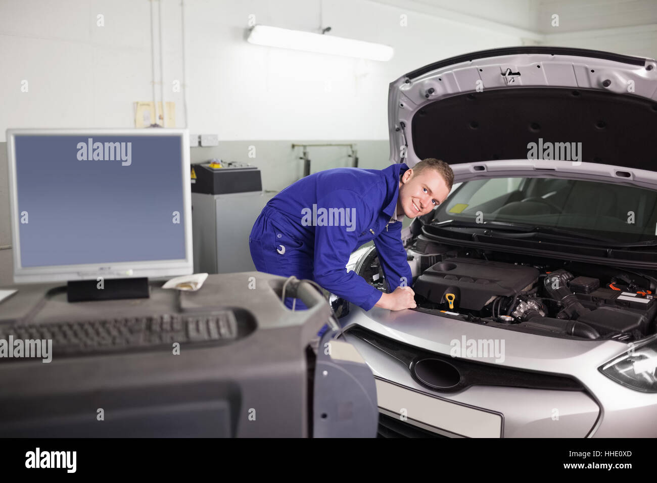 Smiling mechanic examining an engine of a car in a garage Stock Photo ...