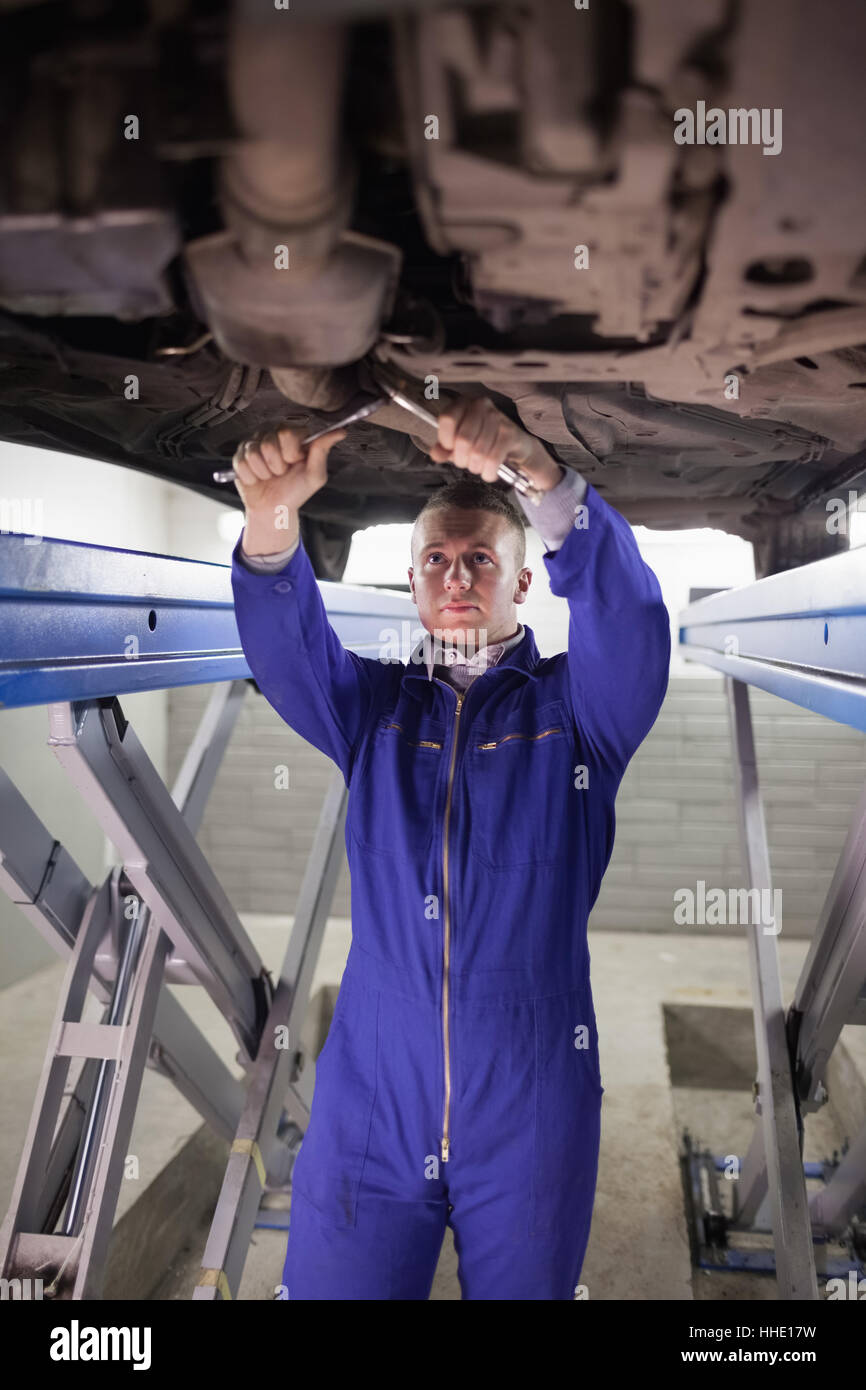 Concentrated mechanic repairing a car with spanners in a garage Stock