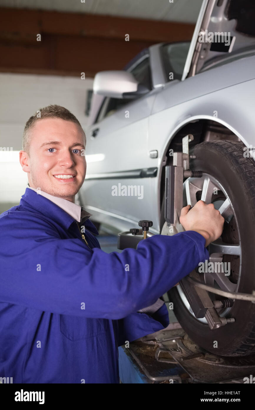 Smiling mechanic repairing a car wheel in a garage Stock Photo - Alamy