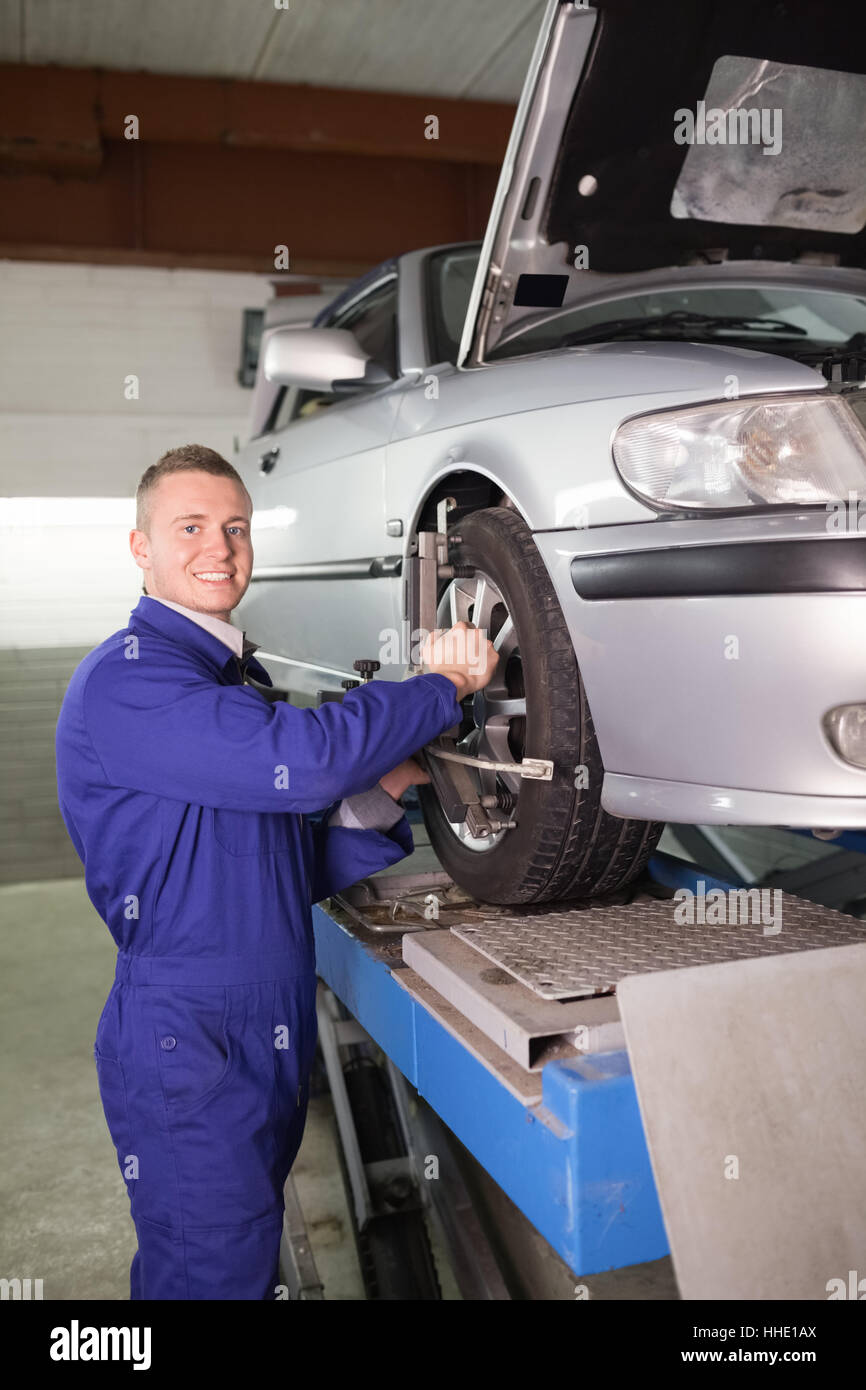Mechanic standing while repairing a car wheel in a garage Stock Photo ...
