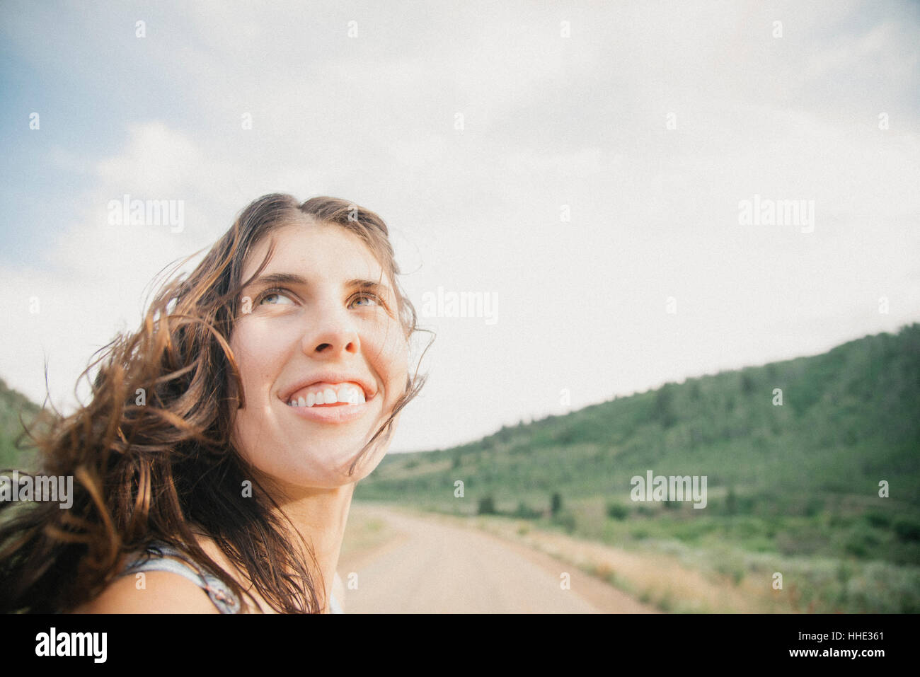 A young woman with windblown hair on a mountain road. Stock Photo