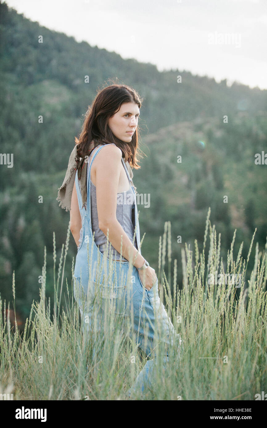 A woman in blue dungarees walking through long grass. Stock Photo