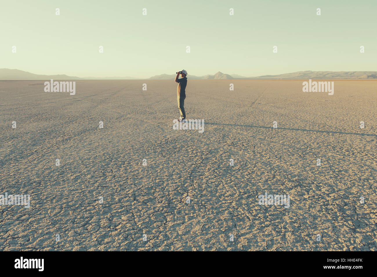Man standing in remote desert, looking through binoculars, Black Rock Desert, Nevada Stock Photo