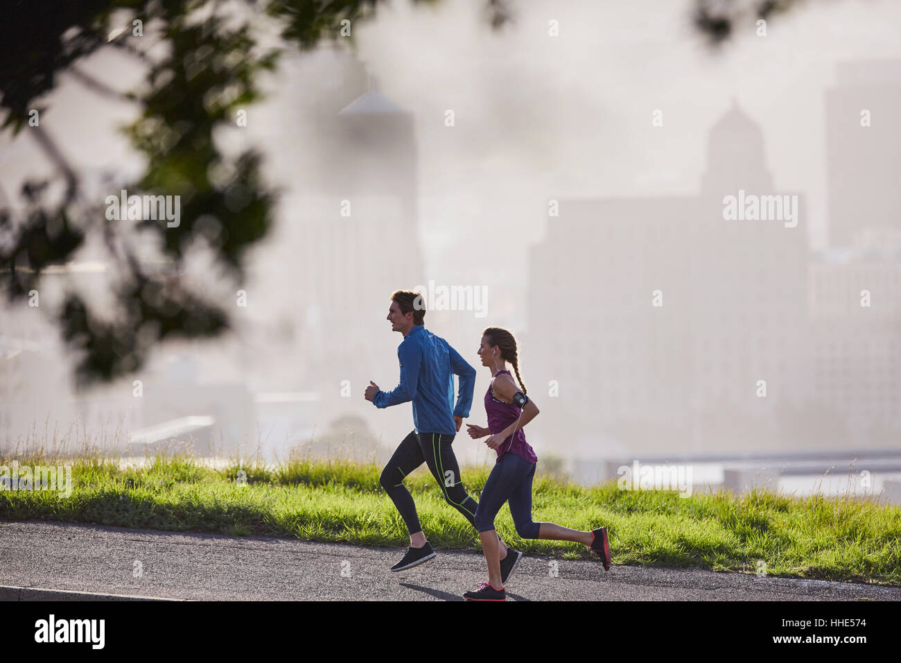 Runner couple running on sunny urban city street Stock Photo