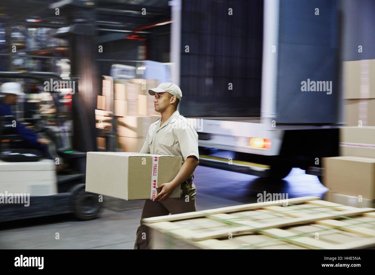 Worker carrying cardboard box at distribution warehouse loading dock Stock Photo