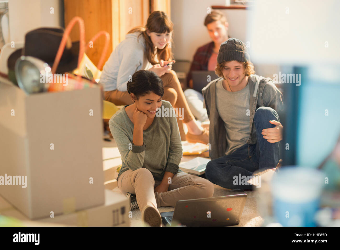 Young couples roommates using laptop unpacking moving boxes in new