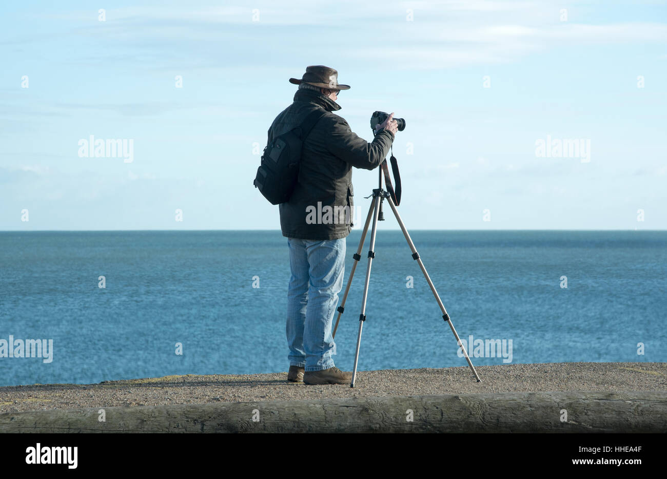 Man using a camera on a tripod to take a seascape picture on the