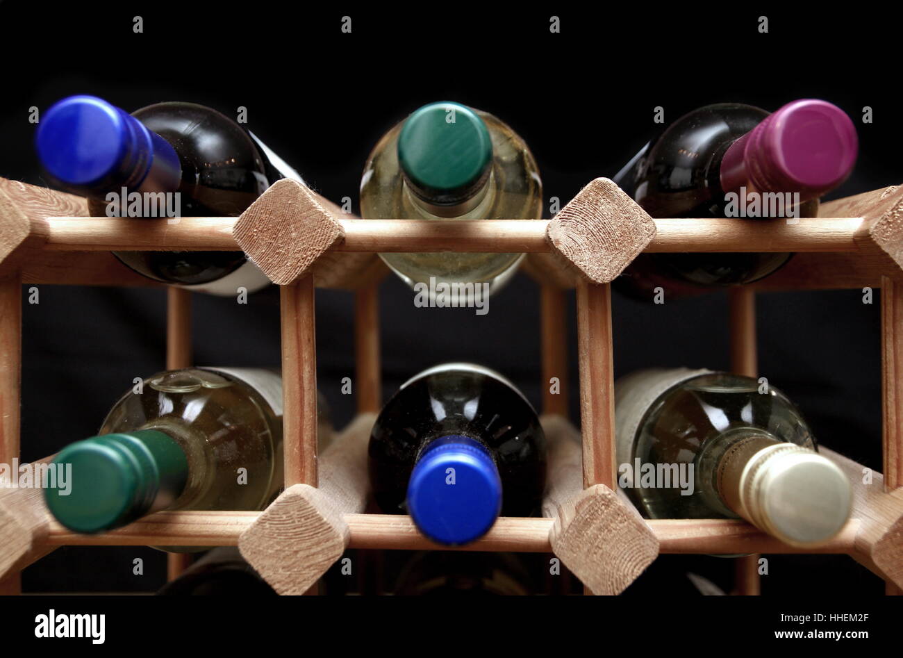 Wooden wine rack with various color bottle tops on black background Stock Photo