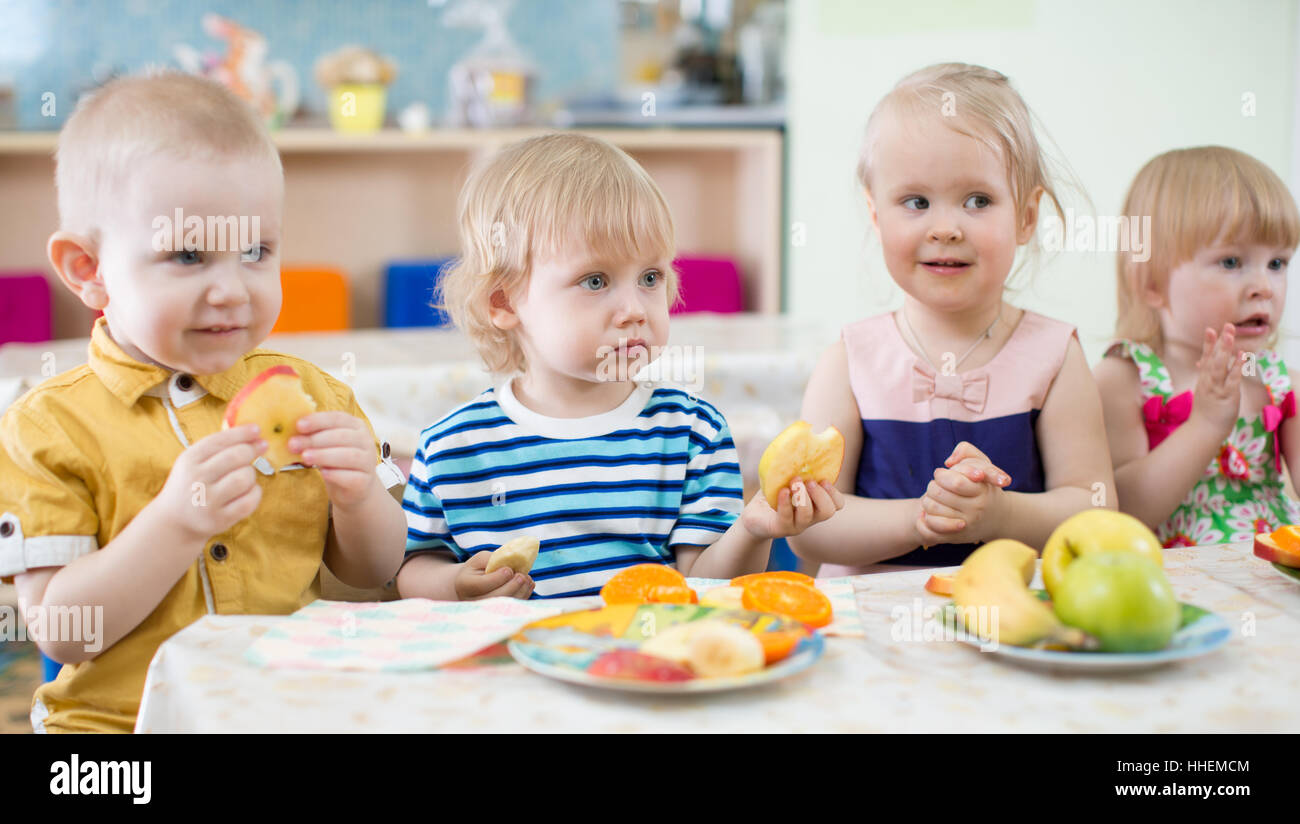 funny kids eating fruits in kindergarten dinning room Stock Photo