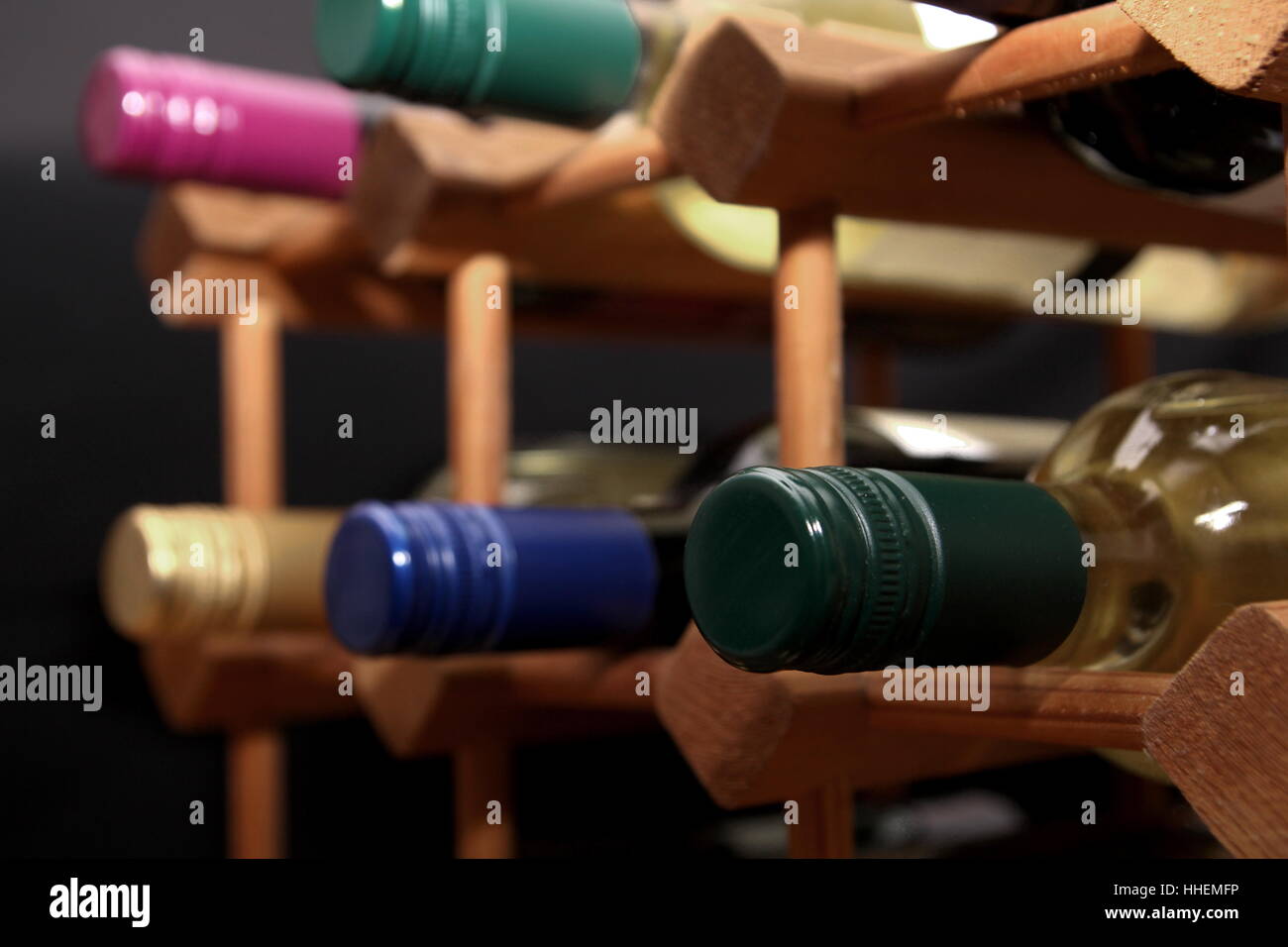 Close up of green screw top wine bottle with other bottles in a wooden wine rack Stock Photo