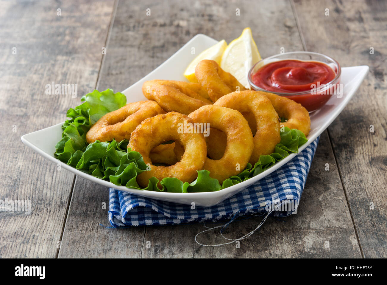 Fried calamari rings with lettuce and ketchup on wooden background Stock Photo