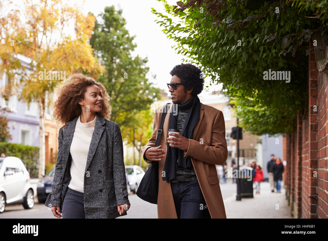 Stylish Young Couple Walking Along Fall Street In City Stock Photo