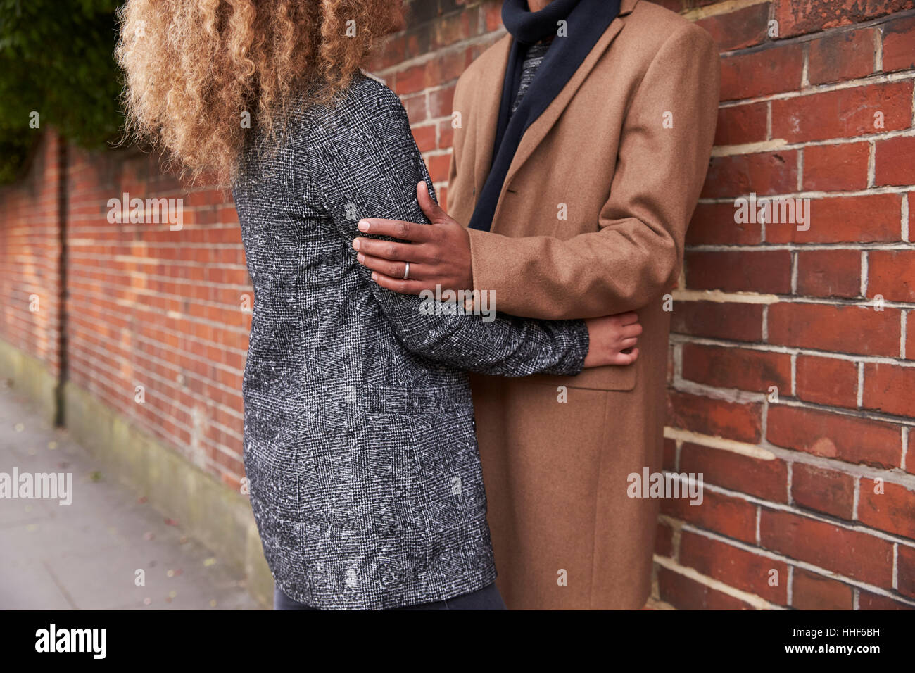 Close Up Of Couple Standing By Wall On Street And Hugging Stock Photo