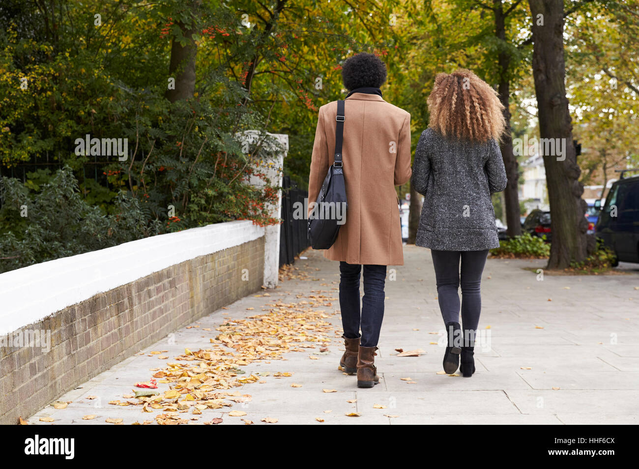 Rear View Of Stylish Couple Walking On Fall Street In City Stock Photo