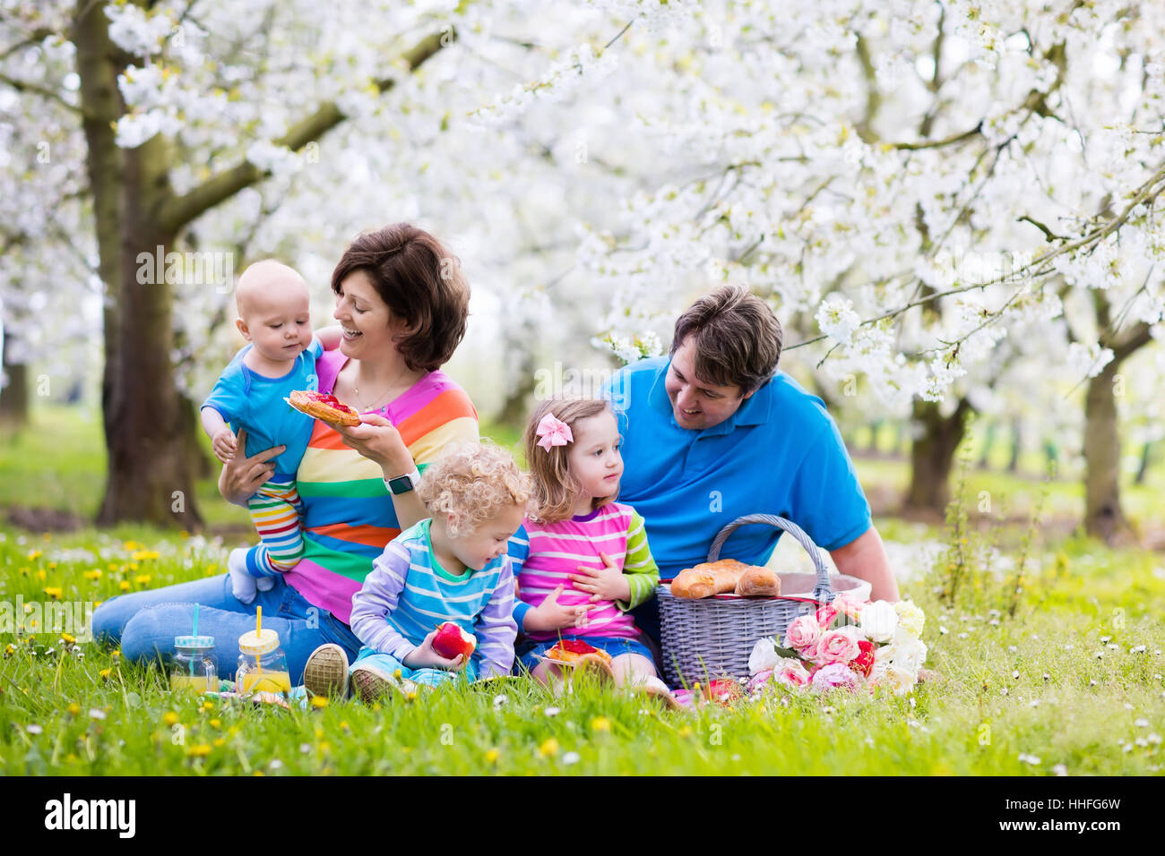 Big family with three little children eating lunch outdoors. Parents