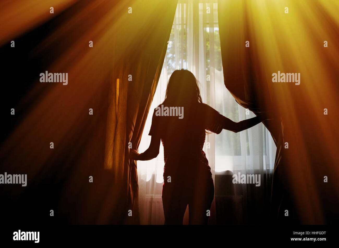 silhouette of young woman looking out the window Stock Photo