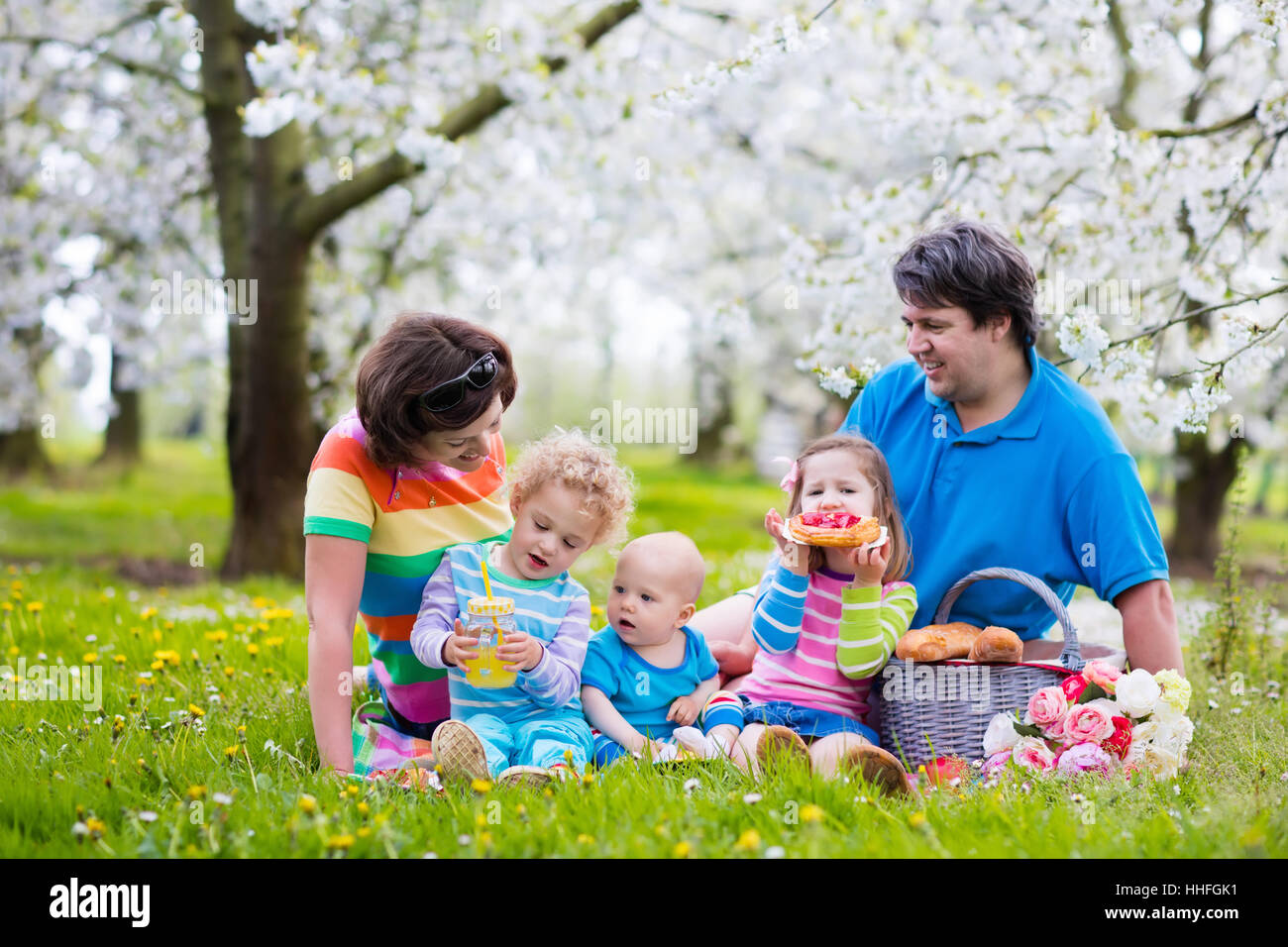 Big family with three little children eating lunch outdoors. Parents