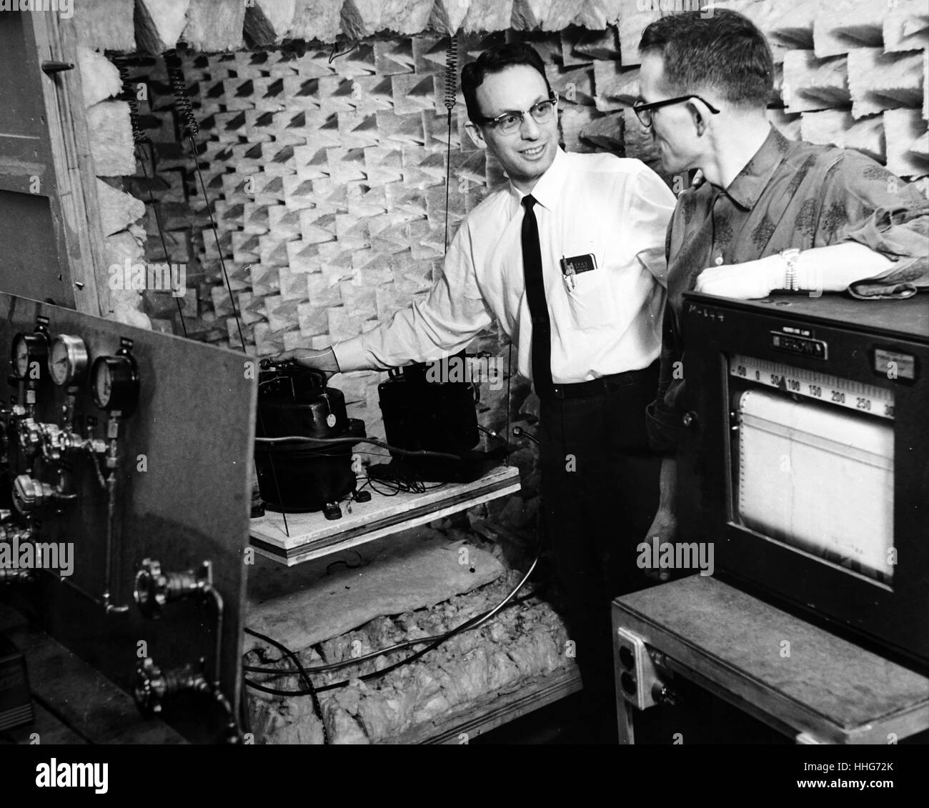 Tracing sources of refrigerator noise; Prof. Raymond Cohen and graduate student Paul Ukrainetz place two compressors (cooling units) inside the anechoic chamber. Recording device at right marks temperatures of the compressors. Stock Photo