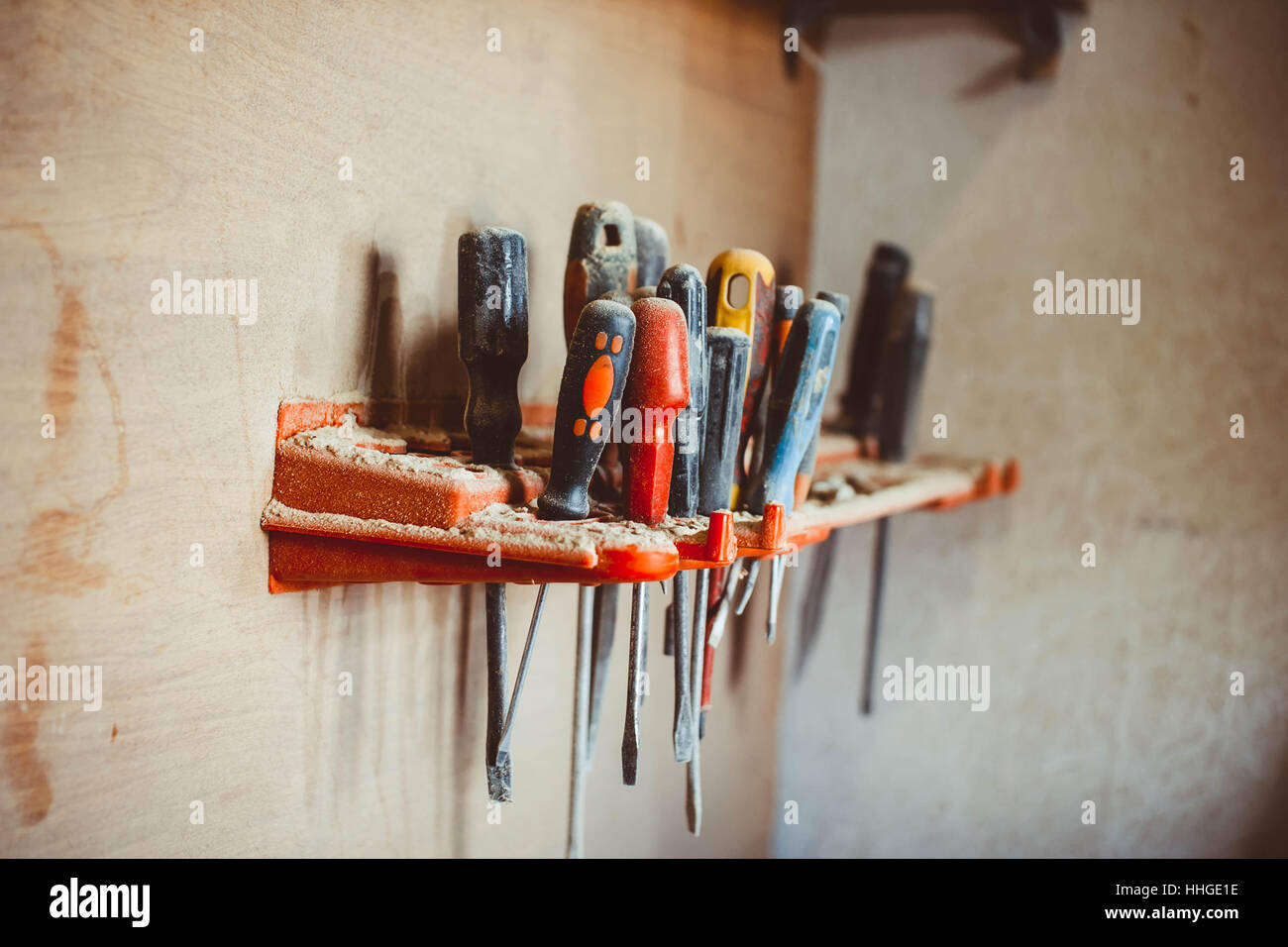 several screwdrivers hanging on wooden wall at workshop Stock Photo