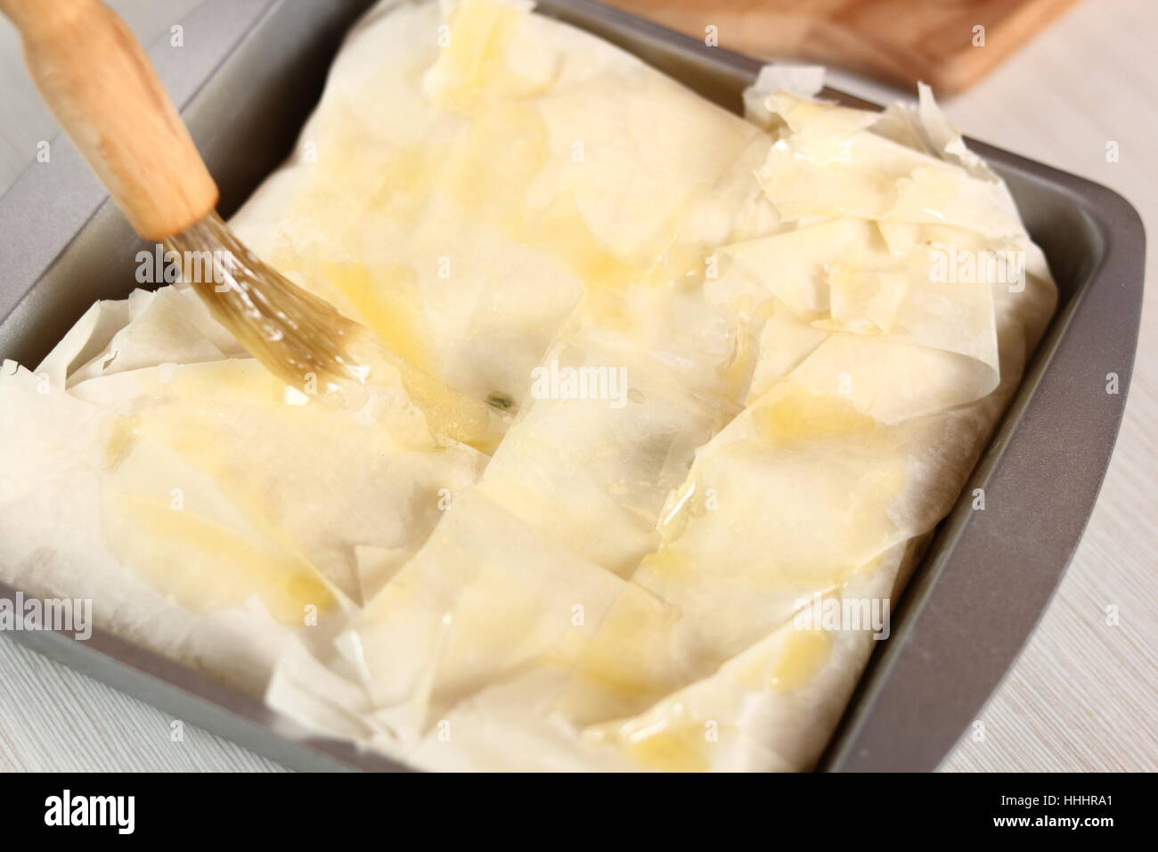 Brush top of pastry of with melted butter. Making Potato and Leek Filo Pie. Series. Stock Photo