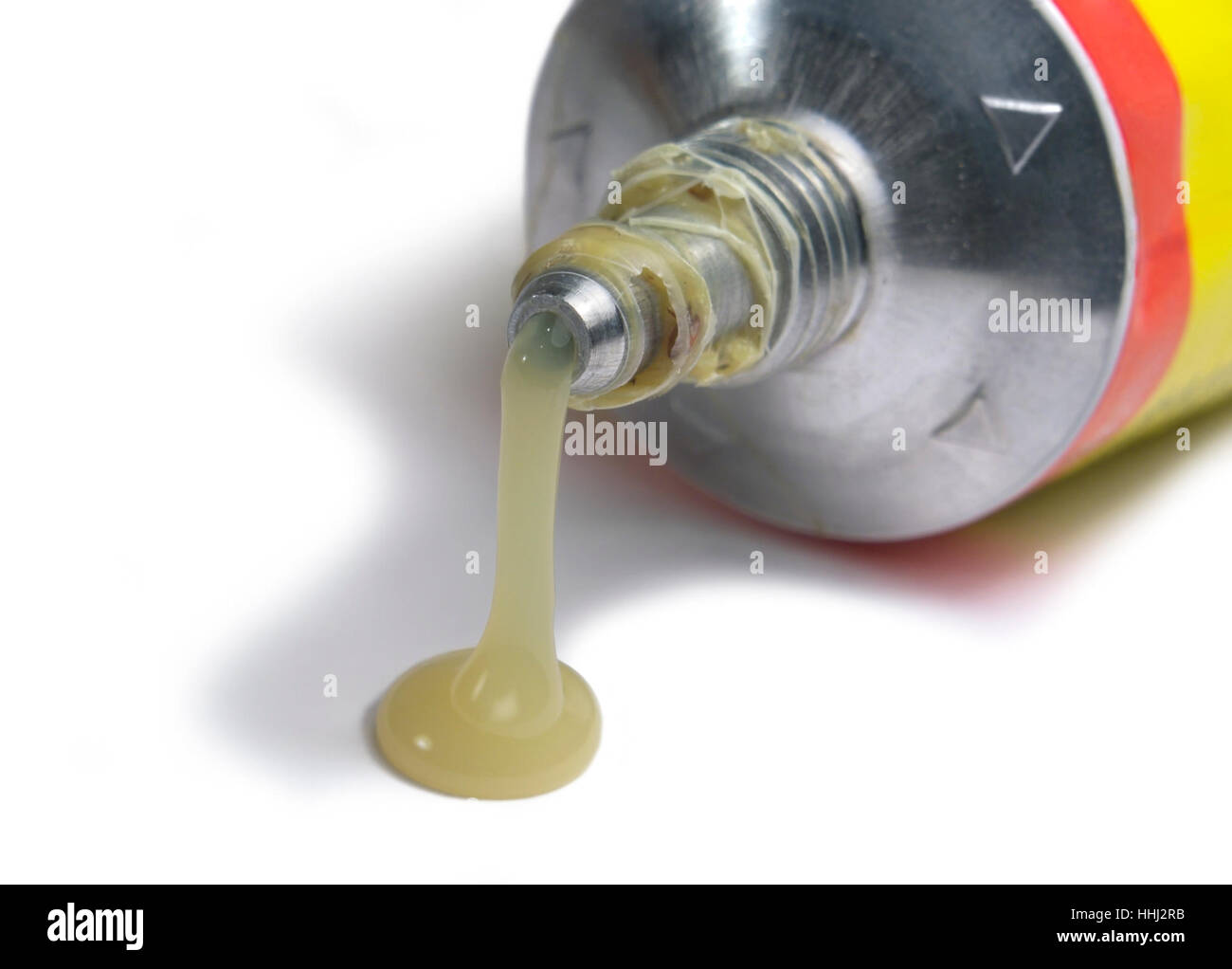 studio photography of a glue tube tip with flowing glue in white back