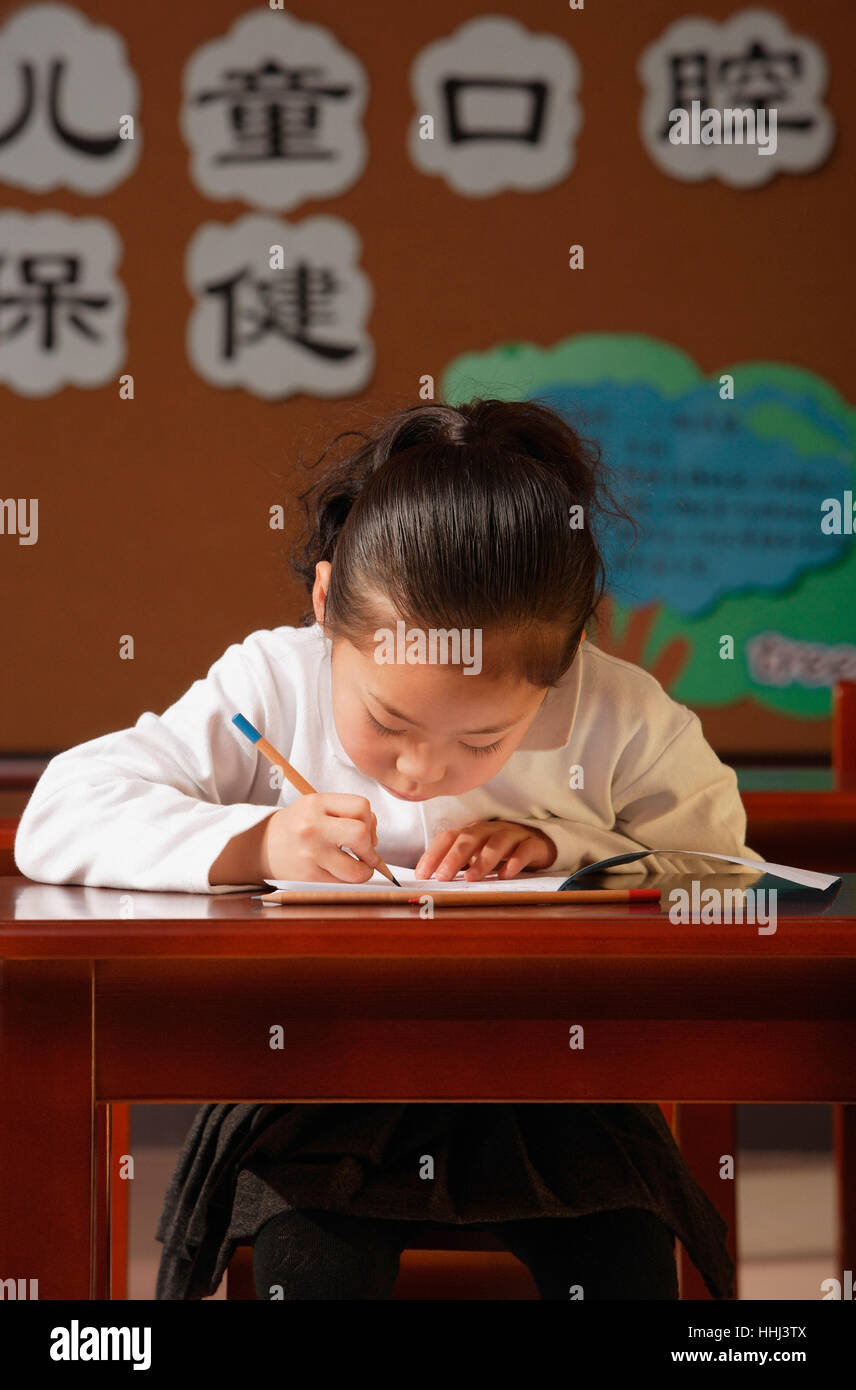 Schoolgirl writing at the desk Stock Photo - Alamy