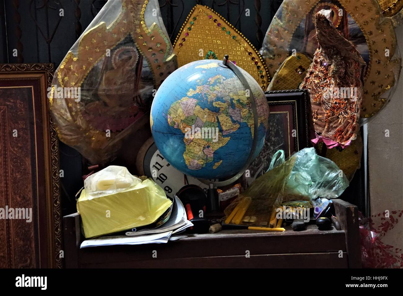 A Monks Cluttered Table with a Globe on it - in the Store Room of a Temple / Pagoda in Battambang Cambodia Stock Photo