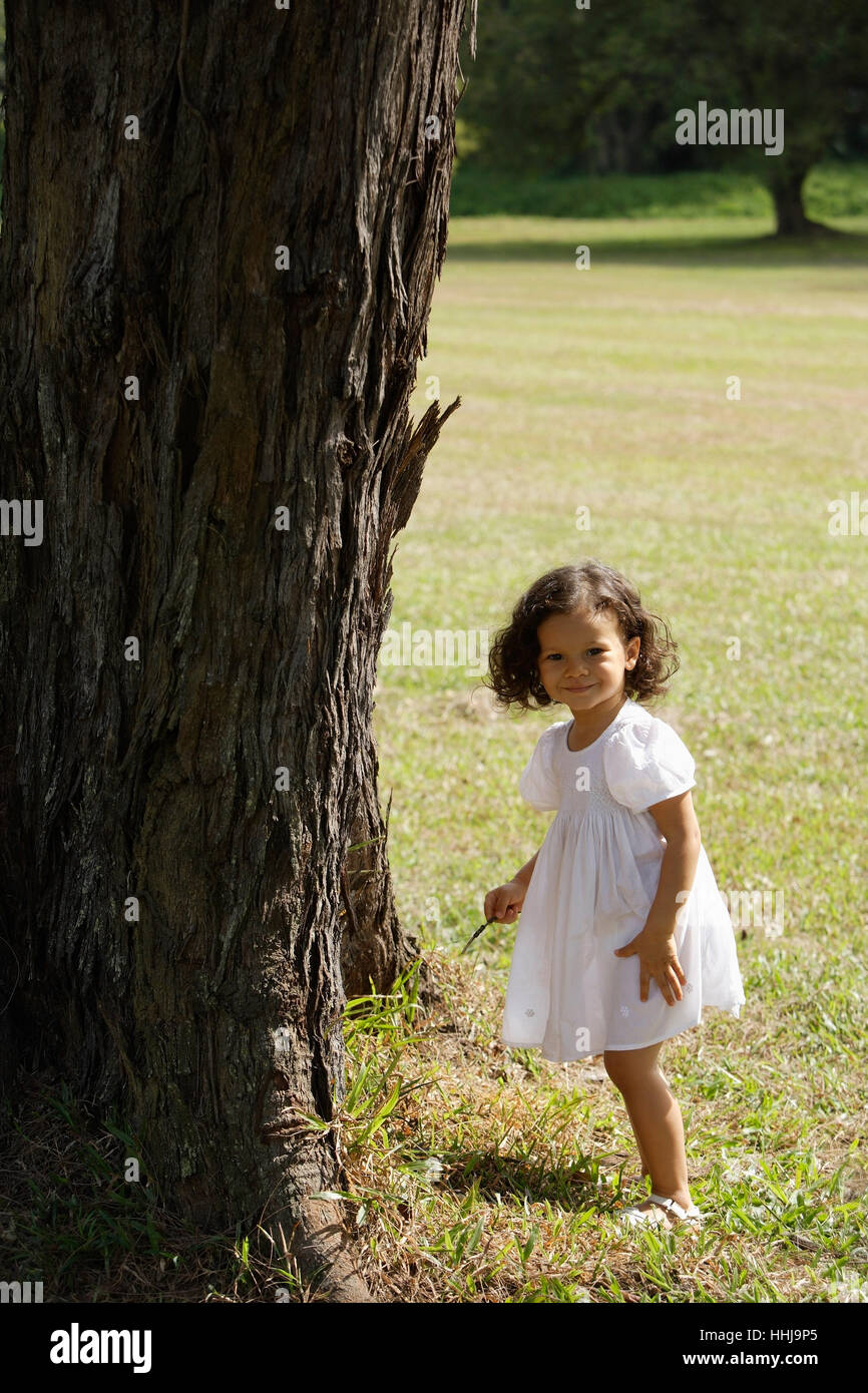 Little girl standing by tree, smiling Stock Photo - Alamy