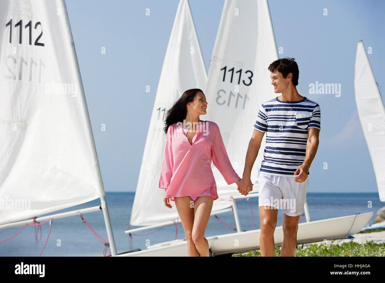 couple walking away from sailboats Stock Photo