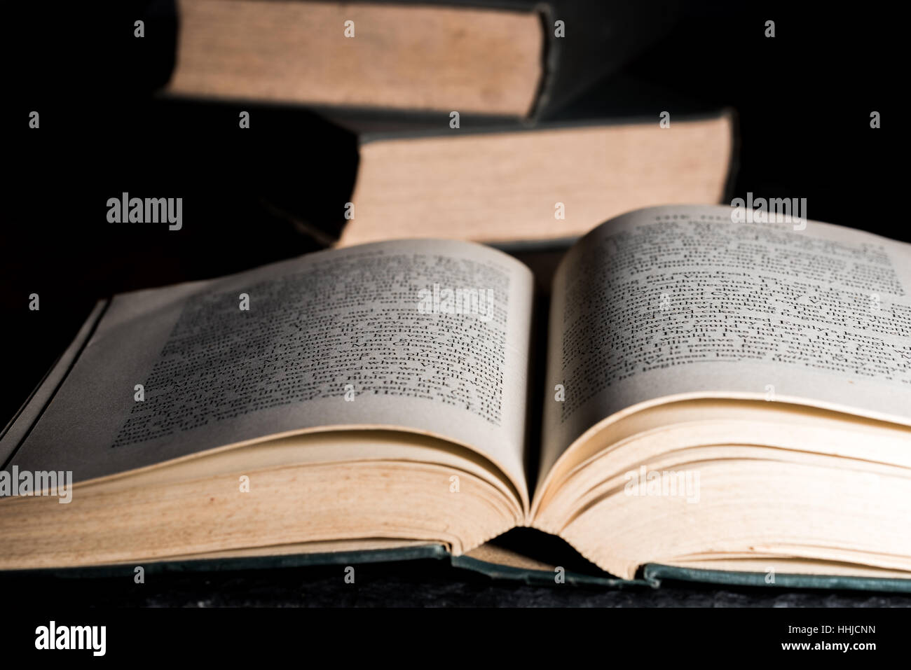 Open book with pile of books behind Stock Photo