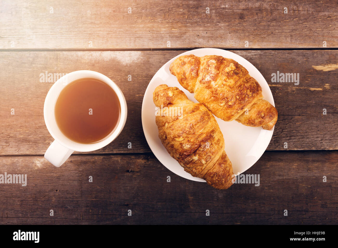 breakfast croissant with cup of tea on wooden table Stock Photo