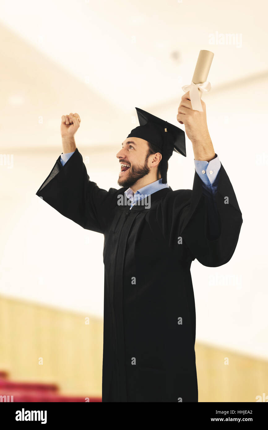cheerful college graduate wearing gown at graduation ceremony Stock Photo