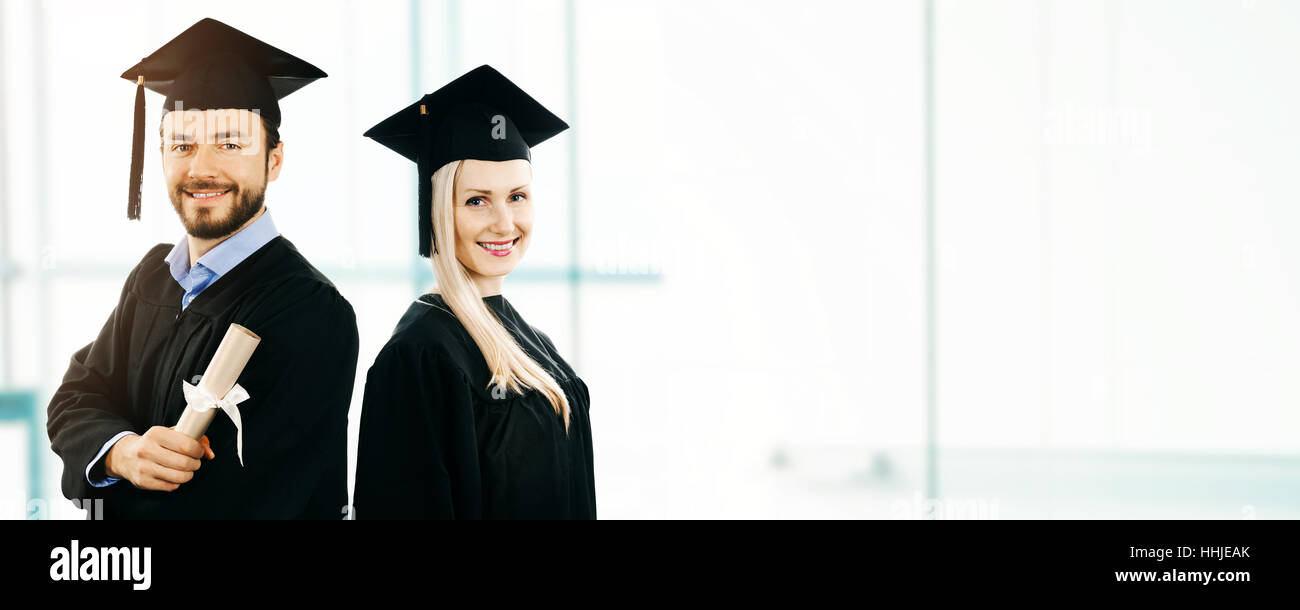 graduation - happy students wearing gown and cap. copy space Stock Photo