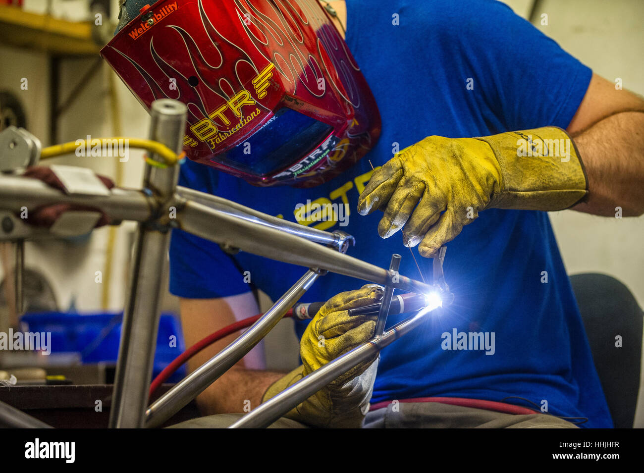 A bespoke steel mountain bike frame is TIG welded in a workshop. Stock Photo