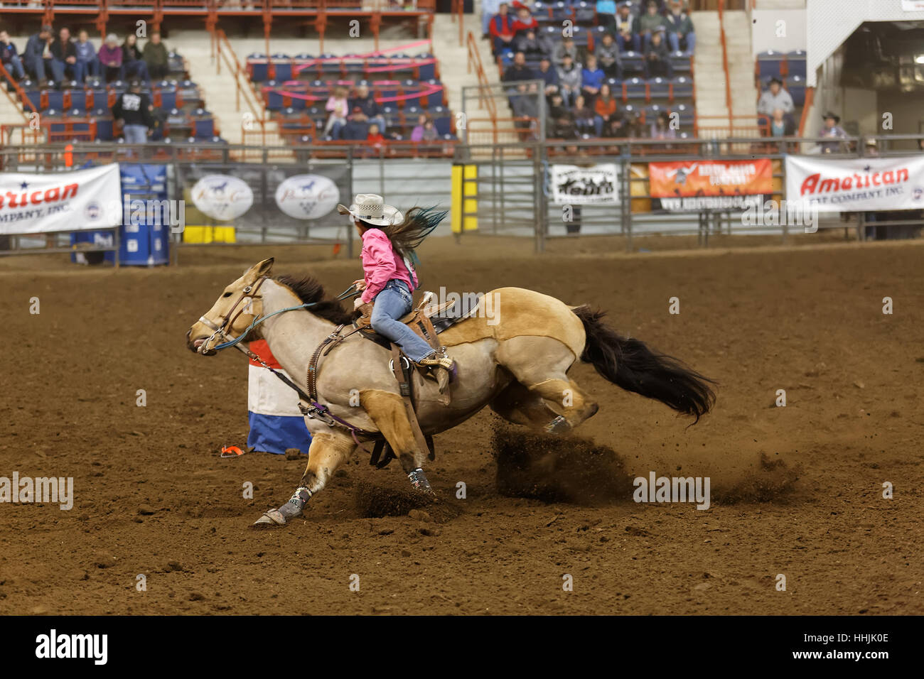 A young cowgirl competes in the high school barrel racing event at the ...