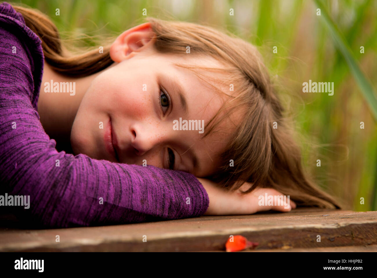 Young girl smiling and being happy. Lying on arms in a pose. Stock Photo