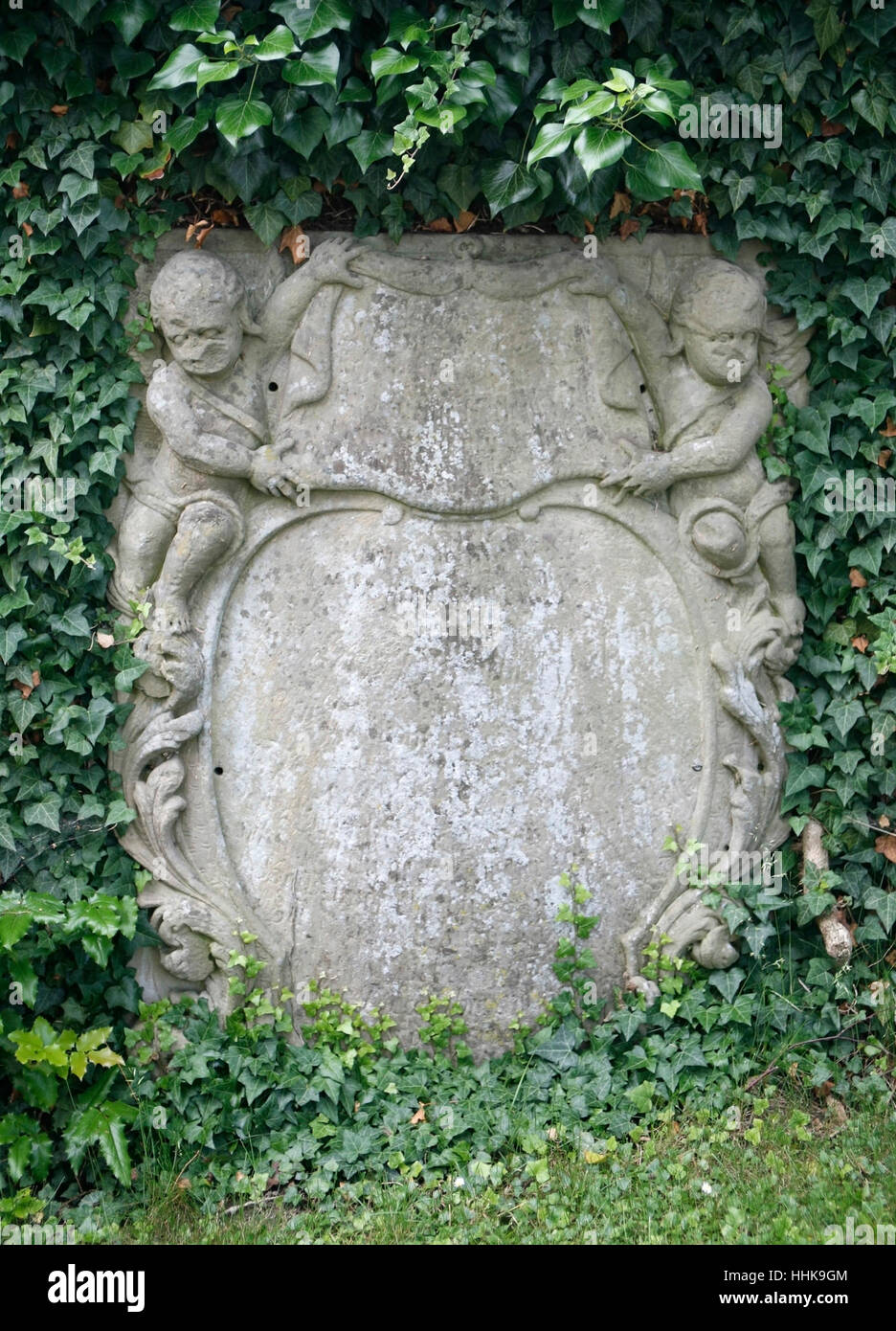 old memorial stone with cupids and green leaves Stock Photo