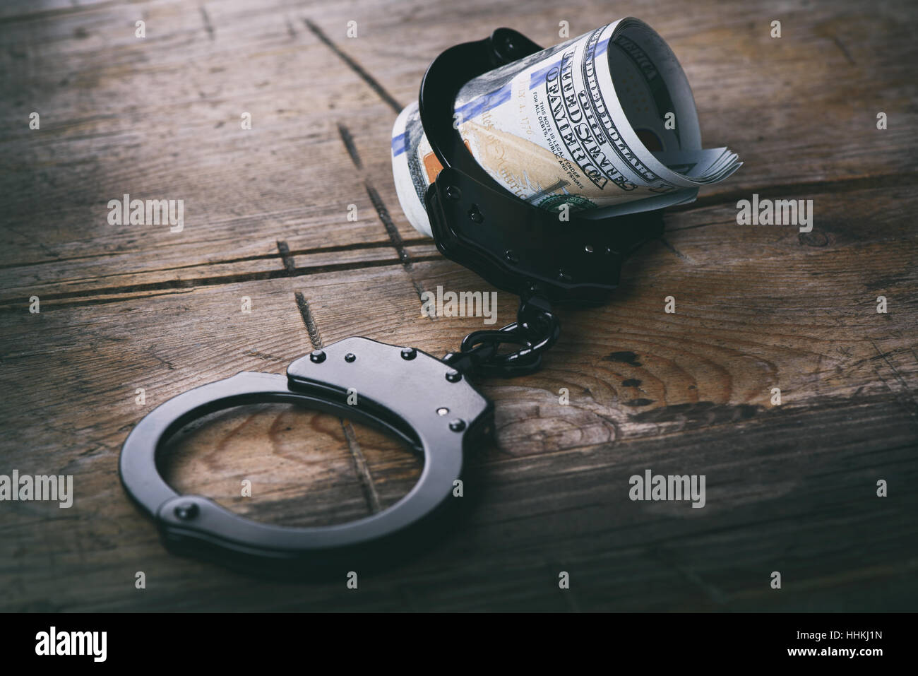 Handcuffs with money on wooden background. US currency Stock Photo
