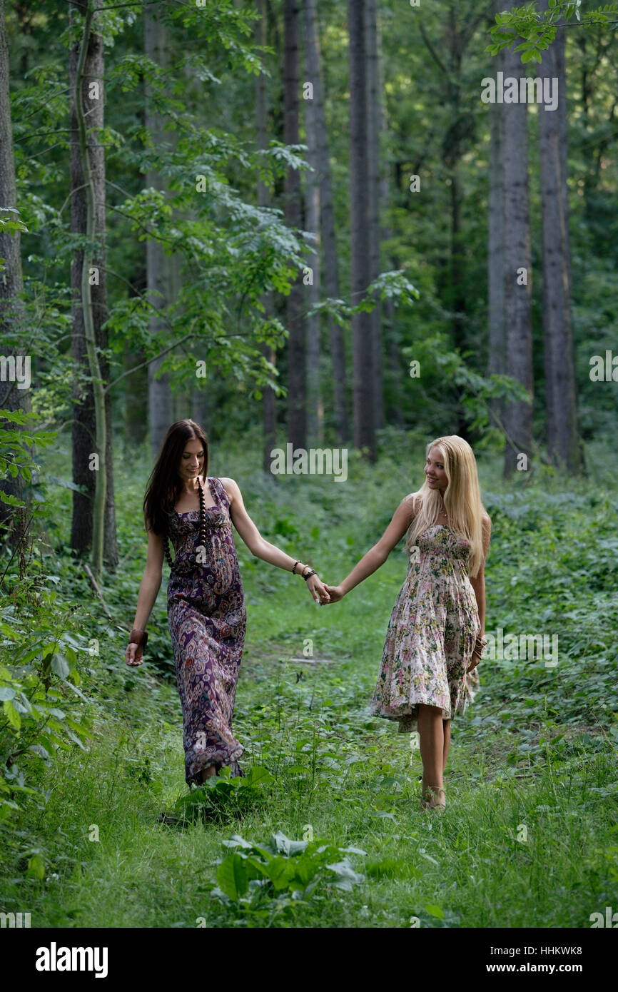 Two young women hand in hand in a forest Stock Photo - Alamy